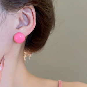 Close-up of pink round stud earrings showing the elegant fit on a model's ear