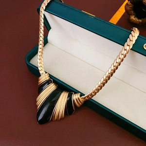 Detail of vintage French gold chain necklace with geometric black enamel pendant in a gift box
