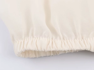 Detailed close-up of cream georgette fabric with layered ruffles and elastic cuff texture