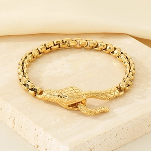 Detailed close-up of golden snake head clasp on a polished box chain bracelet