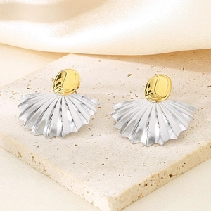 Détail de boucles d'oreilles bicolores dorées et argentées sur un socle en pierre