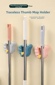 Close-up of three thumb-shaped mop holders in gray, blue and pink colors on a wall