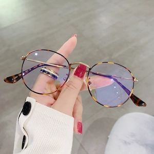 Detail view of tortoiseshell round frames with gold metal temples and blue light lenses