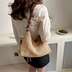 Handwoven straw tote bag with brown leather straps and intricate hollow-out texture
