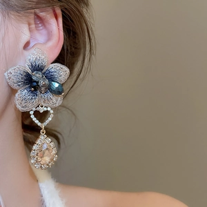 Dettaglio della modella che indossa orecchini a fiore con cristalli blu e strass lucidi