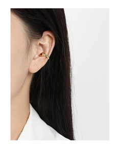 Primo piano di un ear cuff dorato lucido su modella con design curvo minimalista