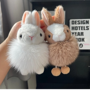 Detail view of plush bunny keychains in white and coffee brown colors with fluffy fur texture