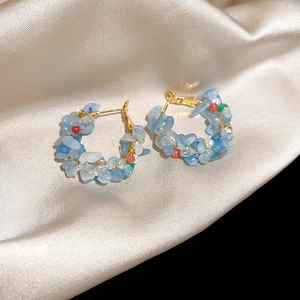 Detailed close-up of light blue natural stone beaded hoop earrings on champagne silk fabric