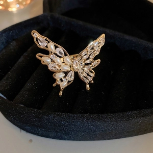 Detailed close-up of golden butterfly ring with pearls and zircons in a black jewelry box