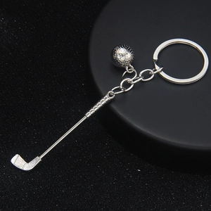 Silver metal golf club and ball keychain accessory for bags on a dark texture background
