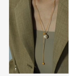 Detaillierte Nahaufnahme einer goldenen Schlangenkette mit weißem Perlenanhänger