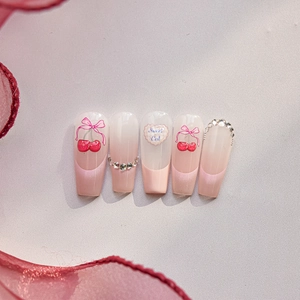 Detail of pink gradient press-on nails with cherry art and rhinestone accents