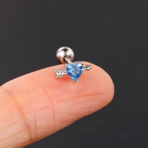 Arrow heart stainless steel ear stud with blue zircon held on a fingertip