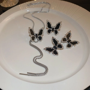 Detail view of silver butterfly necklace and earrings set with black crystal inlay