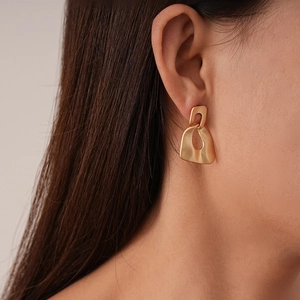 Minimalist matte gold irregular geometric earrings worn by model for an artistic look
