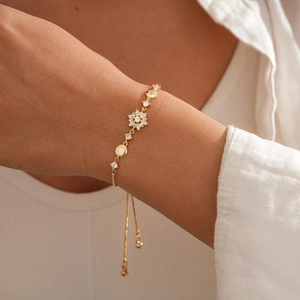 Detail of adjustable gold snowflake bracelet with sparkling zircons on a female wrist