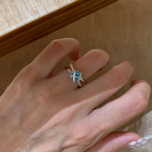 Elegant silver criss-cross open ring featuring a light blue square-cut zircon stone