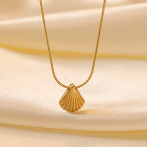 Macro shot of 18k gold plated stainless steel seashell necklace on silk fabric