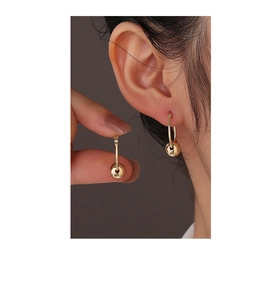 Detailed view of minimalist gold spherical drop earrings on model showcasing polished finish