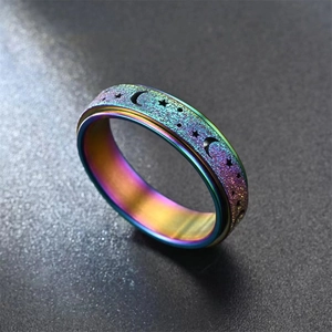 Macro shot of iridescent spinner ring featuring hollow star moon patterns and frosted finish