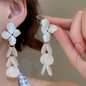 Close-up detail of white acrylic flower drop earrings with translucent bead tassels
