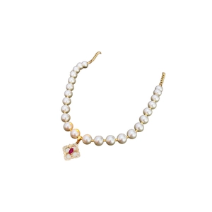 Elegant gold-plated pearl necklace featuring a square red gemstone pendant on white background
