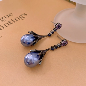 Detail of vintage teardrop pearl earrings with blue crystals and black metal finish