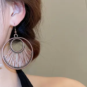 Vintage bohemian hollow geometric circular woven drop earrings worn by a model