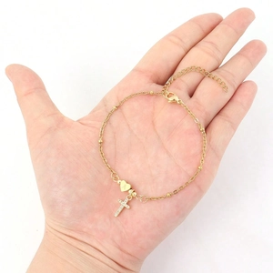 Gold-tone chain bracelet with sparkling cross and letter A heart charm held in hand