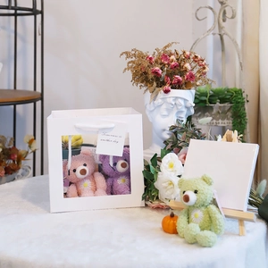 Detail of colorful plush bears in a white window gift bag with decorative props