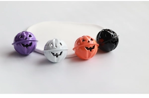 Dettaglio di quattro campanelli a zucca di Halloween in metallo viola, bianco, arancio e nero