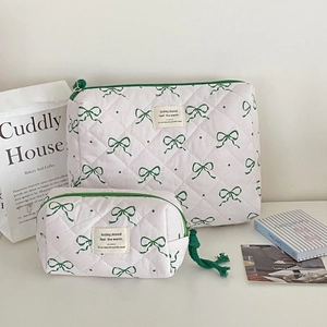 Detailed view of two-piece quilted makeup bags with green bow prints and zipper