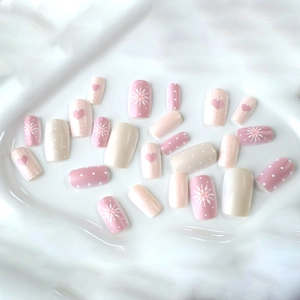 Set di unghie finte rosa con cuori e fiori e pois bianchi su un vassoio display