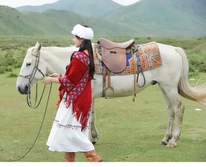 Close-up of red ethnic knit shawl with fringe detailing against mountain scenery