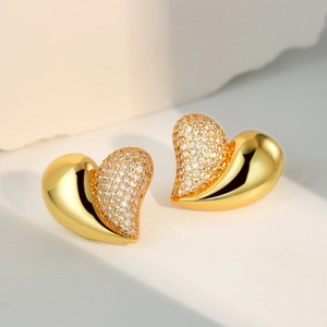 Elegant gold heart stud earrings with cubic zirconia pavé on minimalist background