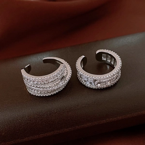 Macro view of silver-toned ear cuffs with clear cubic zirconia on leather base