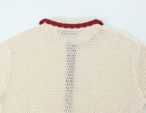 Detail shot of cream knit polo collar with red scalloped edge and delicate hollow texture