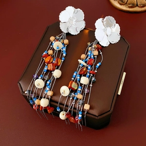 Detail of bohemian tassel earrings with floral silver studs and multi-colored beads