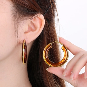 Detail showing amber resin hoop earrings with gold trim and stainless steel posts