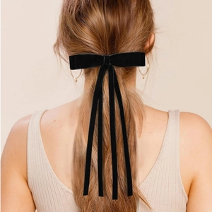 Elegant black velvet bow hair clip with long ribbons shown on model's hairstyle