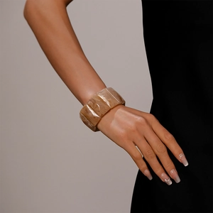 Detail of wide geometric faceted resin bangle with marble texture on model's wrist