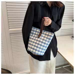 Close-up of blue gingham canvas tote bag with brown PU leather handle and metal hardware
