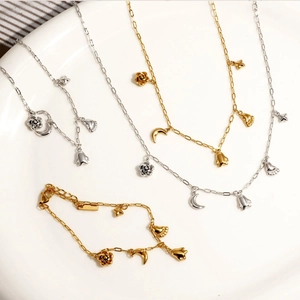 Stylish stainless steel jewelry set with flower and moon pendants on a white plate
