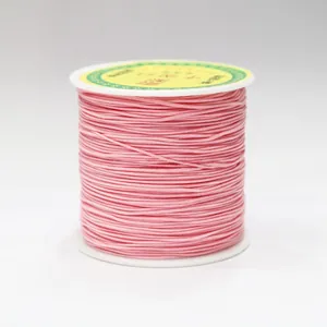 Close-up of 0.8mm pink braided cord for DIY jewelry on a white plastic spool