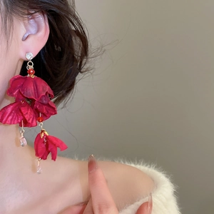 Detail von eleganten roten Blumen-Ohrringen mit Seidenblüten und rosa Kristalltropfen am Modell
