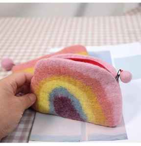 Detail of wool felt rainbow purse with a red zipper and a soft decorative ball pendant