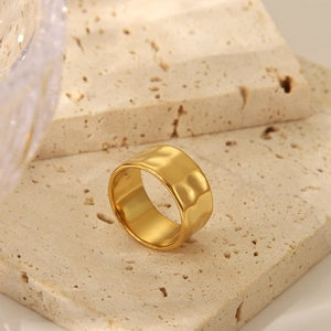 Macro detail of wide gold striped ring on beige travertine stone with wave texture