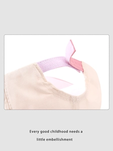 Detail of adjustable hook-and-loop strap on a beige cotton bear ear cap for kids