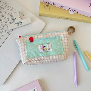 Pink checkered canvas pencil case with mint green pocket shown in desk workspace setup