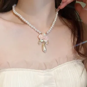Elegant pearl necklace with pink ceramic roses and teardrop pendant on female model